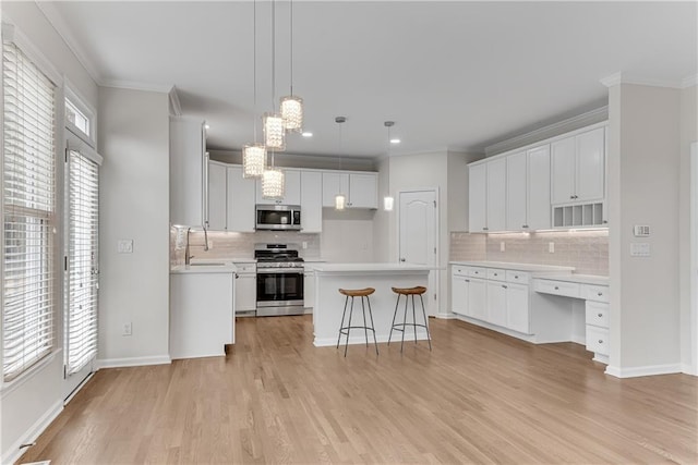 kitchen featuring a healthy amount of sunlight, a center island, crown molding, light wood-type flooring, and appliances with stainless steel finishes