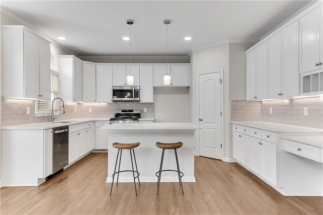 kitchen featuring light wood-style flooring, a sink, stainless steel appliances, white cabinetry, and crown molding