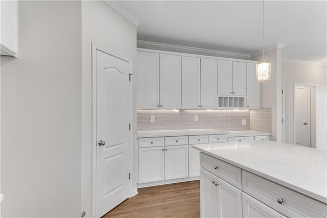 kitchen with white cabinetry, light countertops, light wood finished floors, and ornamental molding