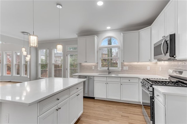 kitchen with ornamental molding, a sink, backsplash, stainless steel appliances, and light countertops