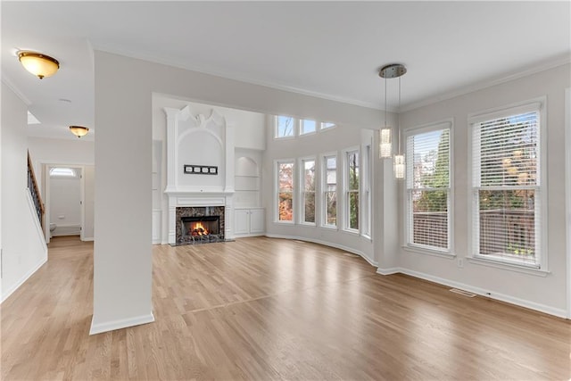 unfurnished living room with built in shelves, light wood-type flooring, baseboards, and ornamental molding