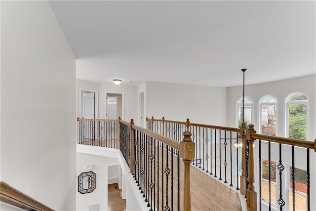 hall with an upstairs landing and light wood finished floors