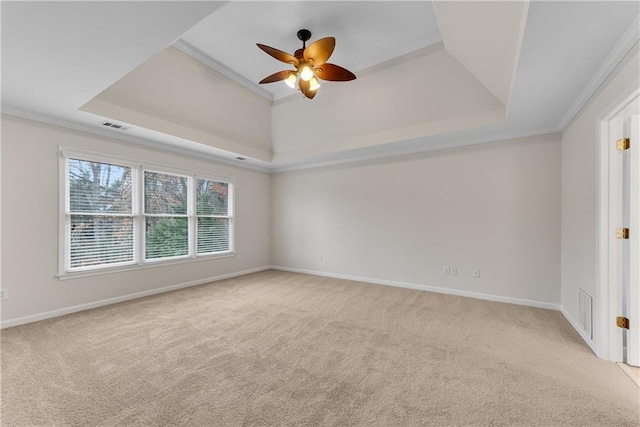 empty room with a raised ceiling, baseboards, visible vents, and light carpet