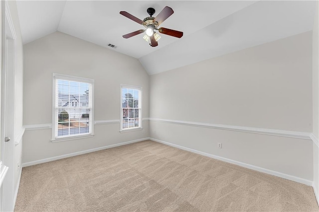 carpeted spare room with a ceiling fan, lofted ceiling, baseboards, and visible vents