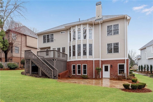 rear view of property featuring brick siding, stairway, a lawn, a chimney, and a deck