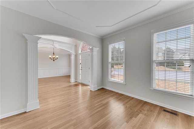 unfurnished room with arched walkways, a notable chandelier, visible vents, and ornate columns