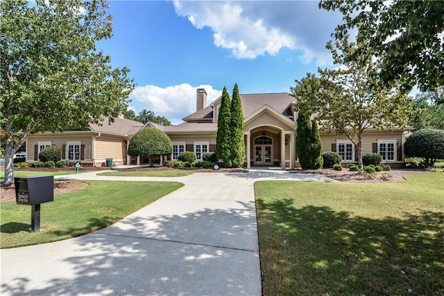 view of front of home featuring french doors, a chimney, and a front yard