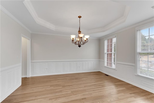 unfurnished room featuring visible vents, a wainscoted wall, a notable chandelier, a tray ceiling, and light wood-style floors