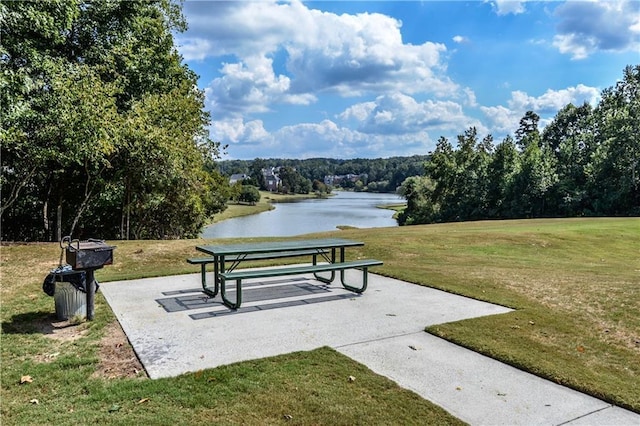 view of community featuring a view of trees, a yard, and a water view