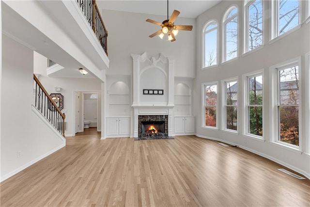 unfurnished living room featuring a high end fireplace, visible vents, baseboards, and light wood-style floors