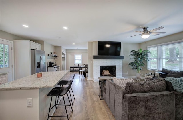 living area with a ceiling fan, recessed lighting, a wealth of natural light, and light wood-style floors