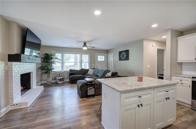 kitchen with a brick fireplace, a ceiling fan, open floor plan, and a kitchen island