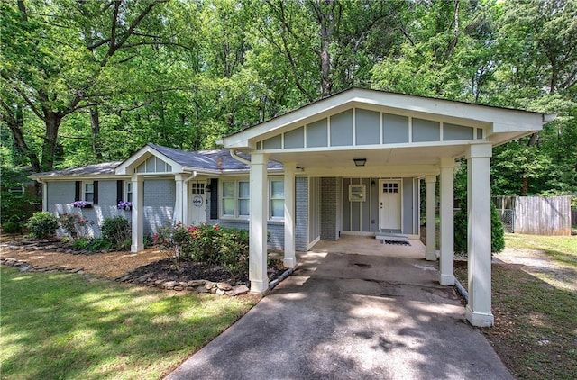 view of front facade with fence, an attached carport, brick siding, and aphalt driveway