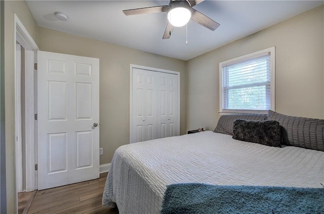 bedroom with baseboards, ceiling fan, wood finished floors, and a closet