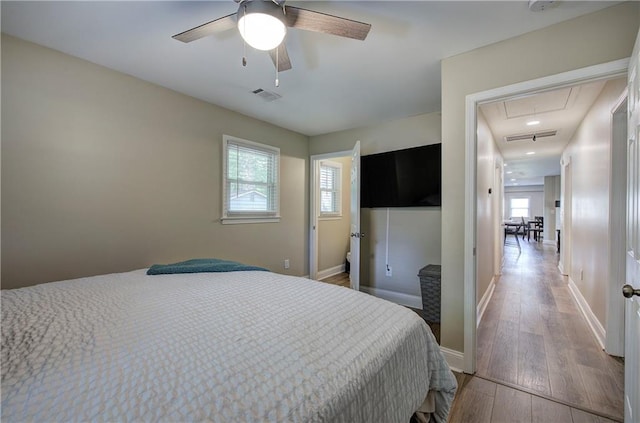 bedroom featuring baseboards, visible vents, light wood finished floors, and attic access