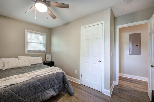 bedroom with baseboards, electric panel, a ceiling fan, and wood finished floors