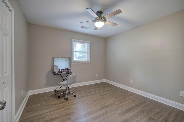 unfurnished office with baseboards, ceiling fan, wood finished floors, and visible vents