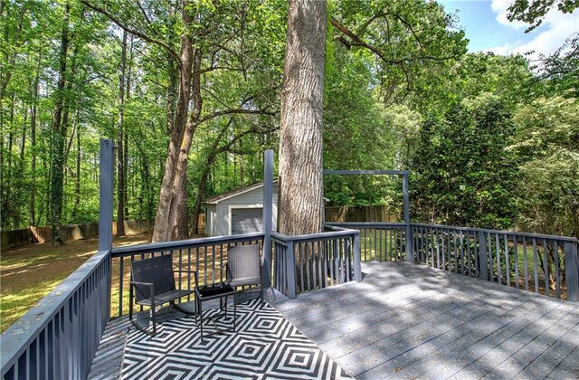 wooden terrace with an outdoor structure, a fenced backyard, and a garage