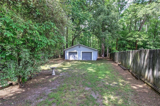 view of yard featuring fence, an outbuilding, and a garage