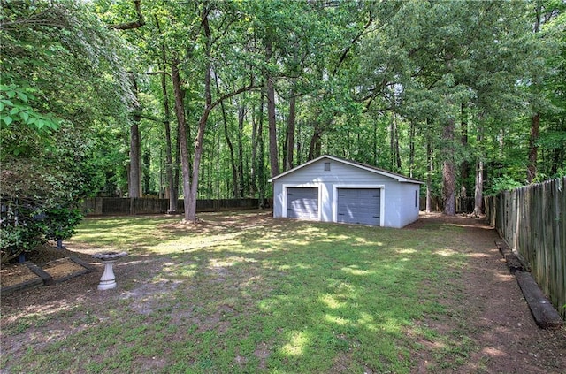 view of yard with an outdoor structure, a fenced backyard, a view of trees, and a detached garage