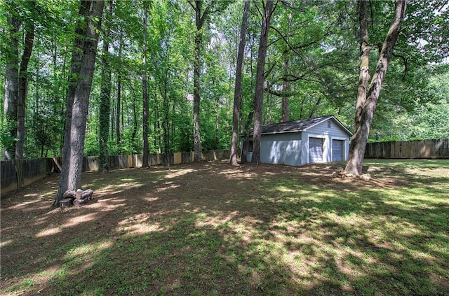view of yard with a garage, an outbuilding, and a fenced backyard