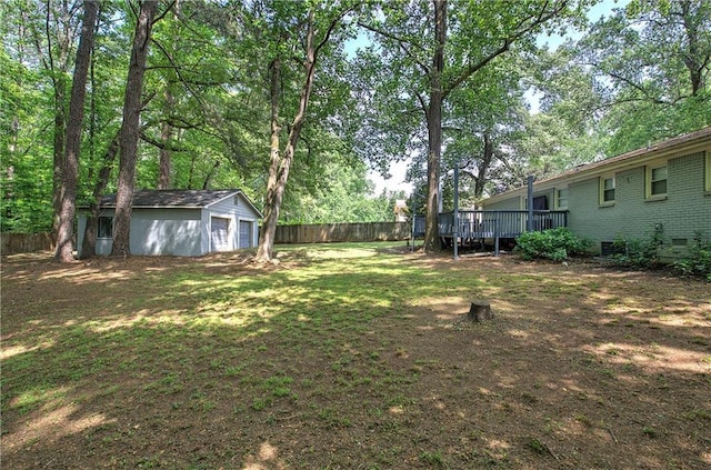 view of yard with a garage, an outbuilding, a fenced backyard, and a wooden deck