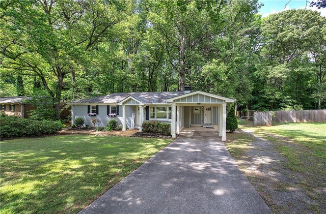 ranch-style home featuring covered porch, a front yard, fence, aphalt driveway, and an attached carport