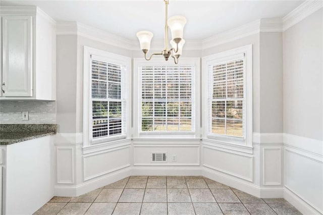 unfurnished dining area featuring light tile patterned floors, ornamental molding, a wealth of natural light, and a chandelier