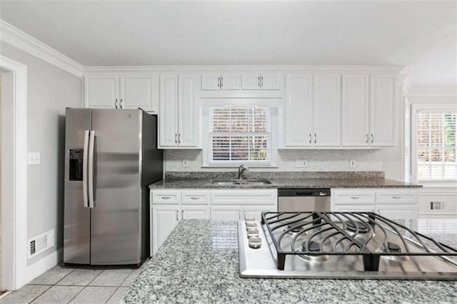 kitchen featuring light stone countertops, stainless steel appliances, crown molding, sink, and white cabinetry