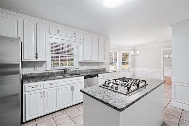 kitchen with white cabinetry, sink, decorative backsplash, a kitchen island, and appliances with stainless steel finishes