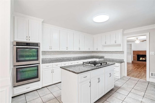 kitchen with dark stone counters, white cabinets, stainless steel appliances, and a kitchen island