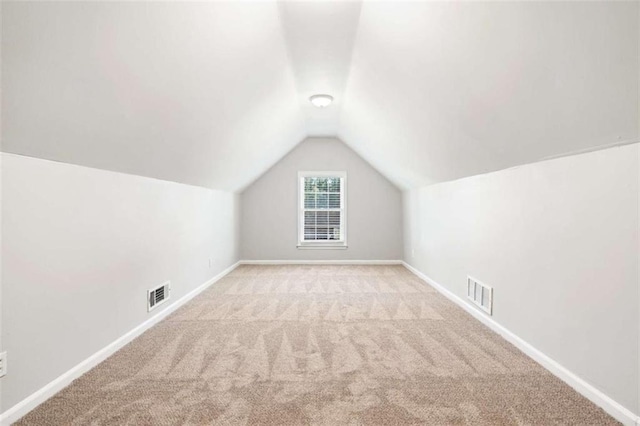 bonus room with lofted ceiling and light carpet