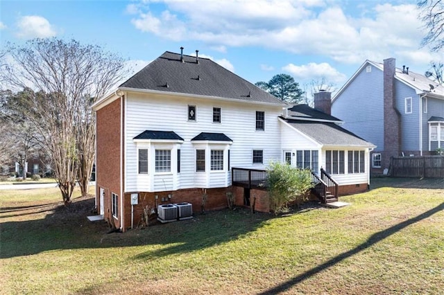 rear view of house featuring a lawn, a sunroom, a wooden deck, and central AC