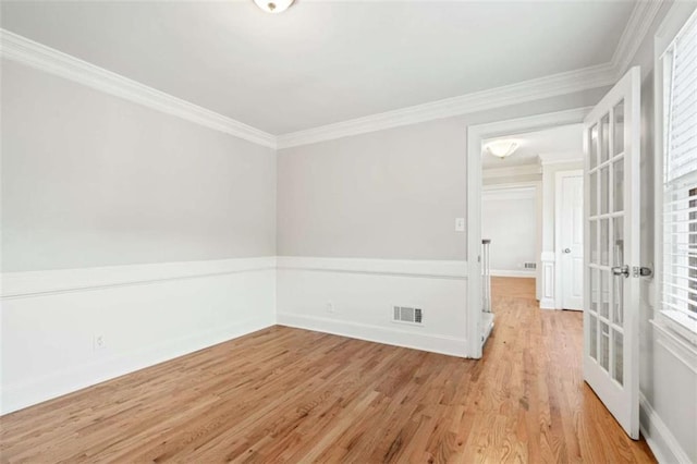 empty room featuring french doors, crown molding, and light hardwood / wood-style flooring