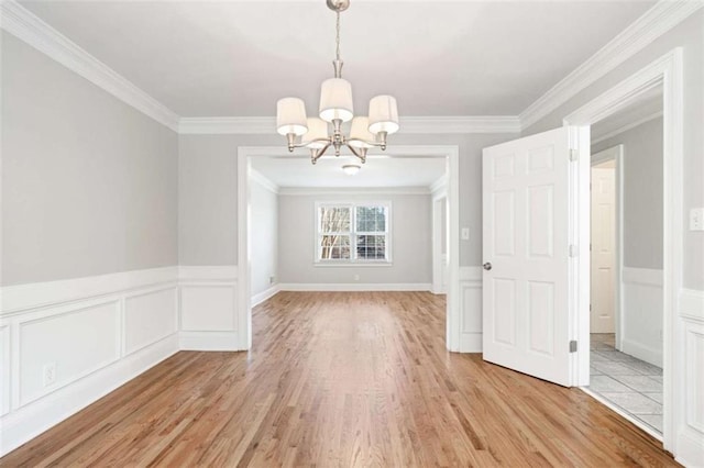 unfurnished dining area featuring a chandelier, crown molding, and light hardwood / wood-style flooring