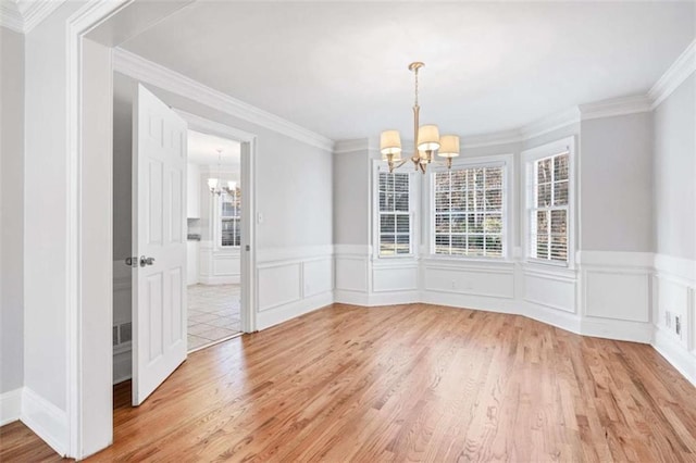 unfurnished dining area with hardwood / wood-style floors, ornamental molding, and an inviting chandelier