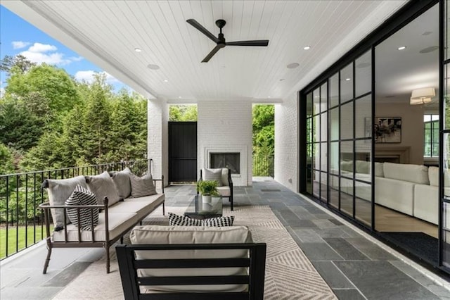 view of patio / terrace with an outdoor living space with a fireplace and ceiling fan