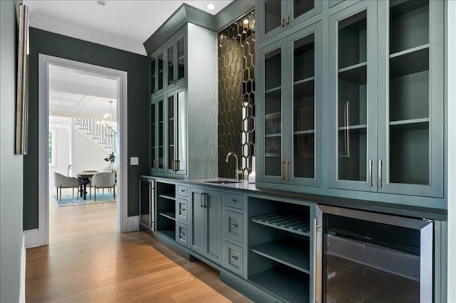 bar with wine cooler, light hardwood / wood-style floors, and sink