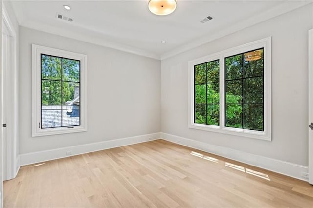 empty room with ornamental molding, a healthy amount of sunlight, and light wood-type flooring