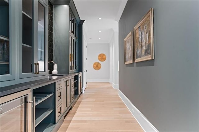 hall featuring ornamental molding, beverage cooler, light hardwood / wood-style floors, and sink