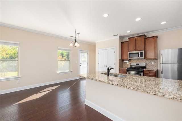 kitchen featuring pendant lighting, ornamental molding, dark wood-type flooring, stainless steel appliances, and a notable chandelier