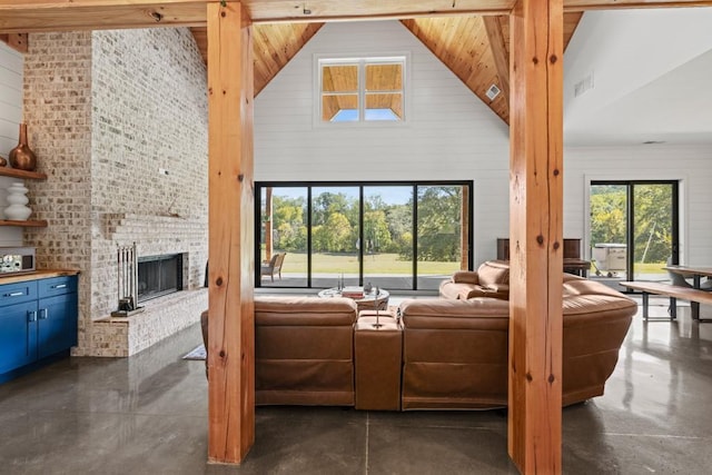 441 Pumpkinvine Rd, Acworth, GA 30101 - living room with visible vents, a brick fireplace, finished concrete flooring, wood walls, and high vaulted ceiling