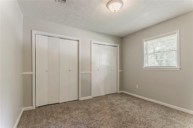 2783 Bicentennial Dr, Stone Mountain, GA 30087 - unfurnished bedroom with two closets, carpet flooring, and a textured ceiling