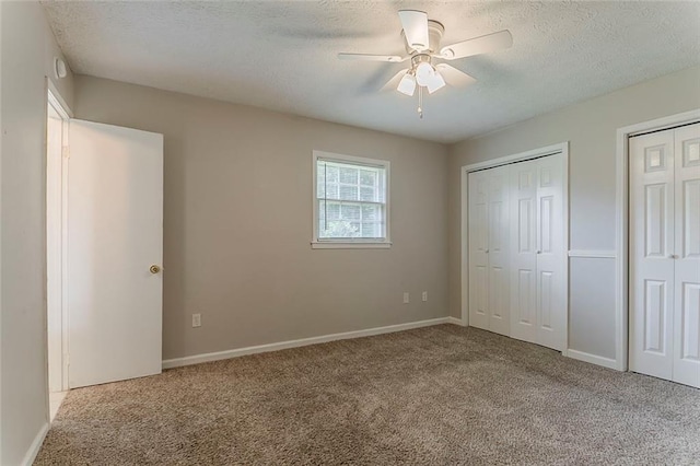 2783 Bicentennial Dr, Stone Mountain, GA 30087 - unfurnished bedroom featuring carpet flooring, two closets, a textured ceiling, and ceiling fan