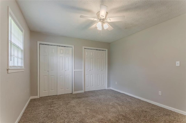2783 Bicentennial Dr, Stone Mountain, GA 30087 - unfurnished bedroom with multiple closets, carpet flooring, ceiling fan, and a textured ceiling