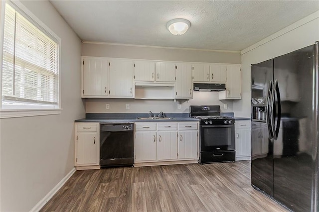 2783 Bicentennial Dr, Stone Mountain, GA 30087 - kitchen featuring black appliances, under cabinet range hood, dark wood finished floors, white cabinets, and dark countertops