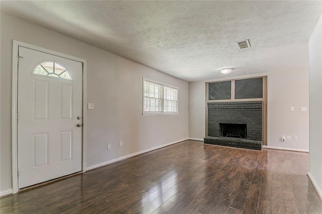 2783 Bicentennial Dr, Stone Mountain, GA 30087 - unfurnished living room featuring wood finished floors, a brick fireplace, and a textured ceiling
