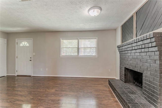 2783 Bicentennial Dr, Stone Mountain, GA 30087 - unfurnished living room featuring wood finished floors, a brick fireplace, healthy amount of natural light, and a textured ceiling