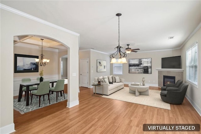 living area with arched walkways, a fireplace, a notable chandelier, visible vents, and light wood-style floors