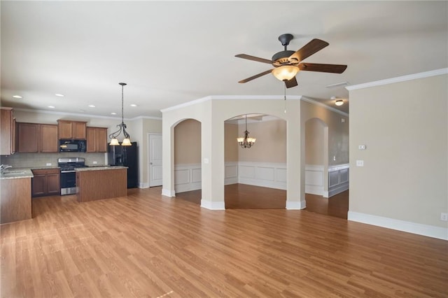 kitchen with arched walkways, a kitchen island, open floor plan, black appliances, and a sink